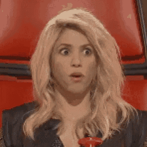 a woman with blonde hair is sitting in a red chair with her mouth open .
