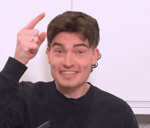 a man in a black sweater is making a funny face and pointing up