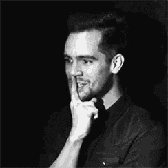 a black and white photo of a man holding his finger to his mouth .