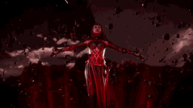 a woman in a red and black costume is standing in a dark room surrounded by red bubbles .