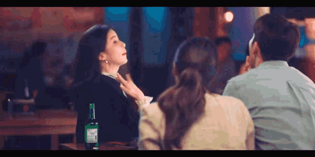 a man and a woman are sitting at a table with a bottle of beer in front of them .