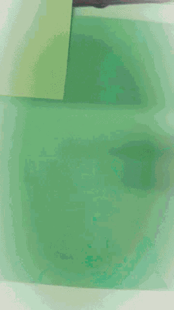 a person is cutting a piece of green paper with a pair of scissors .