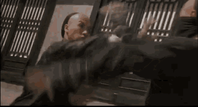 two men are fighting each other in a cage in a movie .