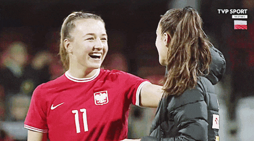 a female soccer player wearing number 11 laughs with another player