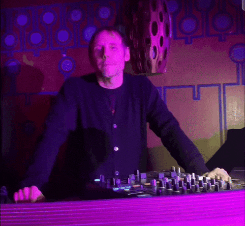 a man in a black sweater is standing in front of a mixer