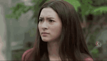 a woman with long hair is making a funny face while standing in front of a tree .