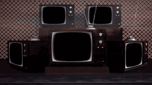 three old televisions are stacked on top of each other in a room
