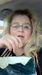 a woman in glasses is eating a bag of chips