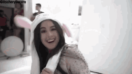 a woman wearing a bunny ear hat is smiling .
