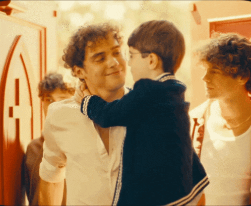 a man holds a little boy in his arms and they are hugging