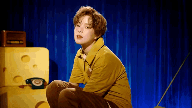 a woman in a yellow shirt is squatting down in front of cheese