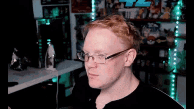 a man with red hair and glasses is sitting in front of a computer