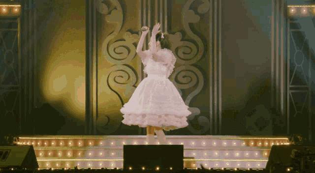 a woman in a white dress is standing on a stage
