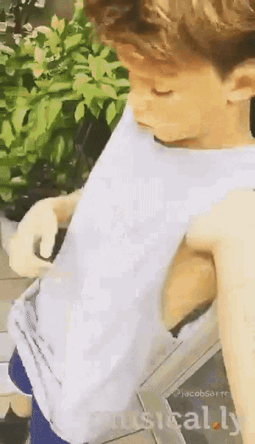 a man in a white tank top is taking a picture of himself