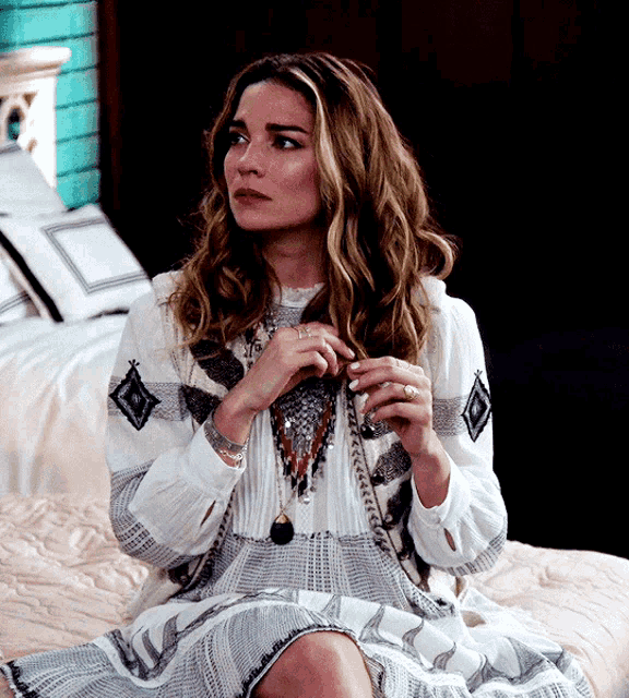 a woman in a white dress is sitting on a bed with her legs crossed