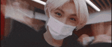 a young man with blonde hair is wearing a white face mask .