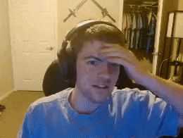 a young man wearing headphones holds his hand to his head