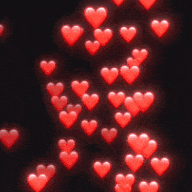 a bunch of red hearts floating in the air on a black background