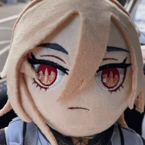 a close up of a stuffed doll with red eyes and a sad look on her face