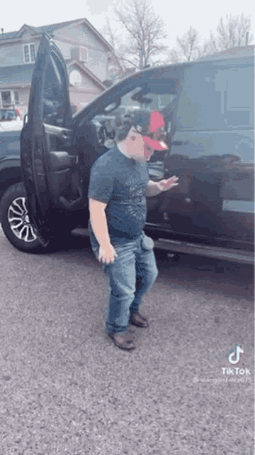 a man in a hat is standing next to a truck with the door open .