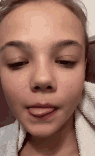 a close up of a girl 's face with her tongue sticking out .