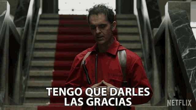 a man in a red suit says tengo que darles las gracias in front of a staircase