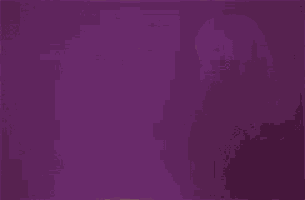 a woman is standing in front of a purple background with her arms crossed .