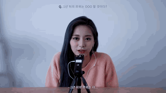a woman sitting at a table with a microphone in front of her and a question in another language