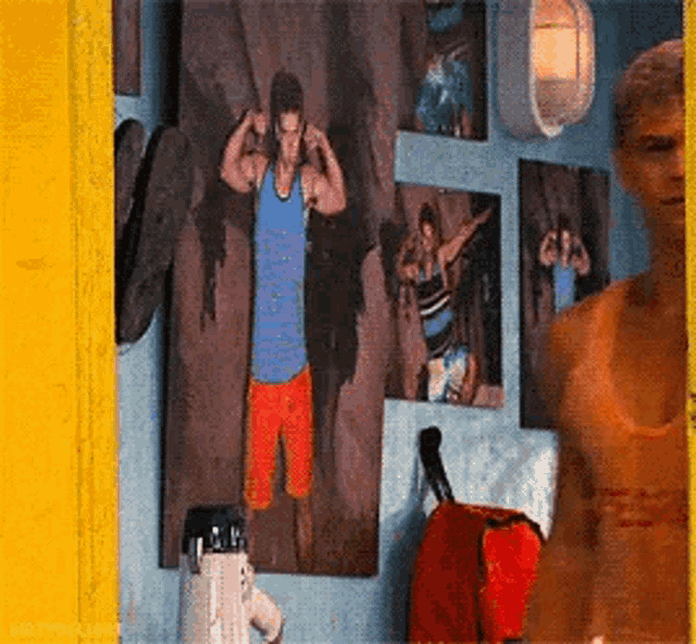 a woman in a bikini is standing in front of a wall with pictures of a man and a woman .