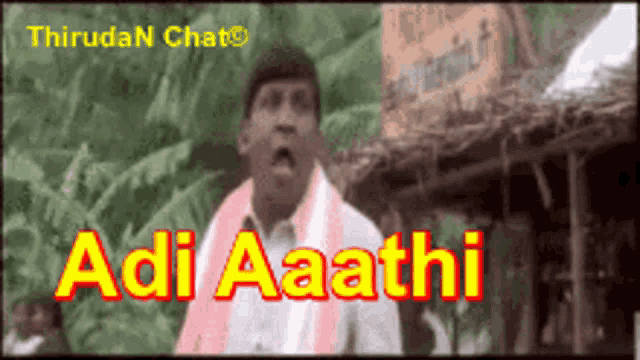 a man with a scarf around his neck is standing in front of a sign that says " adi aaathi "