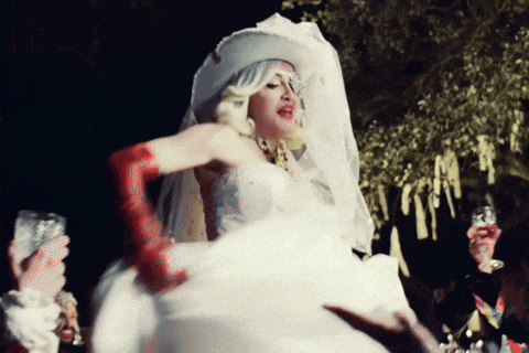 a woman in a white wedding dress and red gloves