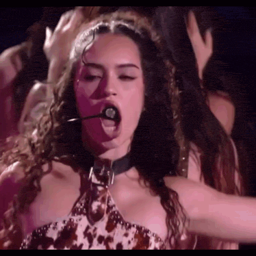 a woman is singing into a microphone while wearing a choker .