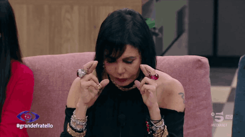 a woman is sitting on a pink couch with the words grandefratello on the bottom