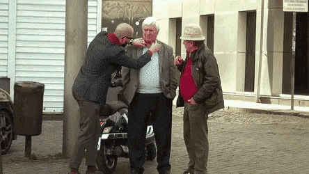 three men are standing in front of a building that has a sign that says ' atencion ' on it