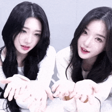 two girls with long black hair are holding their hands out