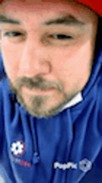 the man is wearing a blue hoodie and a red hat .