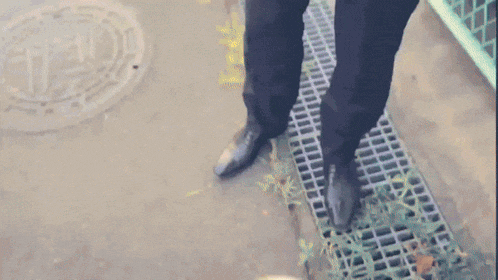 a man walking down a sidewalk with a manhole cover in the background that says ' a ' on it