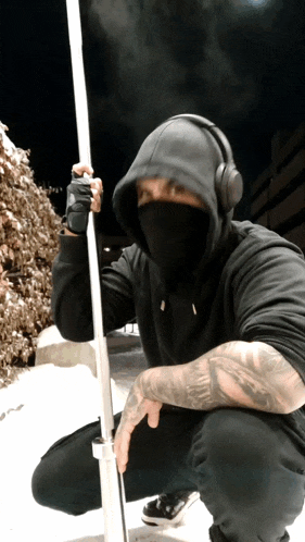 a man wearing a hoodie and headphones holds a pole
