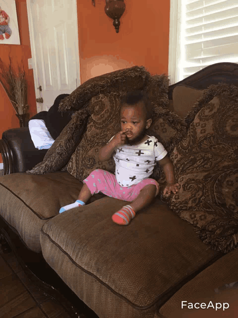 a baby sitting on a couch with faceapp written on the bottom right