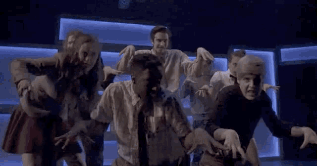 a group of people are dancing in a dark room with a blue light behind them