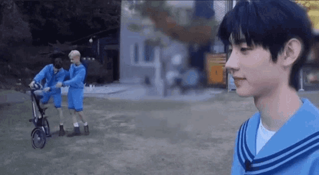 a man in a blue sailor suit is standing in a field next to a stroller .