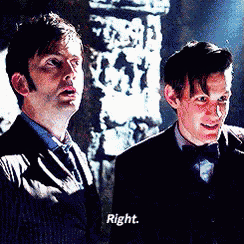 two men in suits and bow ties are standing next to each other in a dark room .