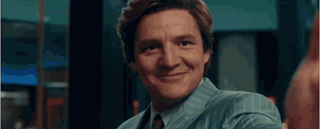 a man in a suit and tie is smiling in a dark room .