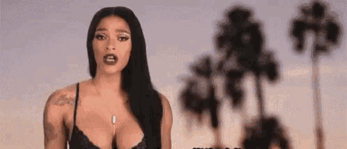 a woman in a bra is standing in front of palm trees in a blurry photo .