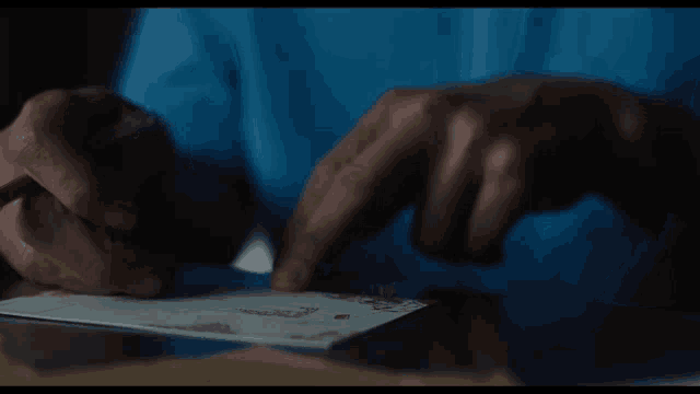 a person is writing on a piece of paper with a pencil