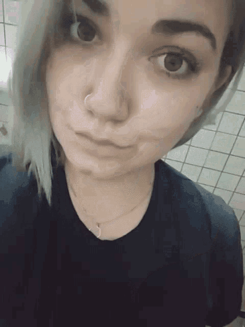 a woman with a nose ring and a black shirt looks at the camera
