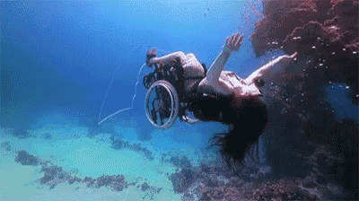 a person in a wheelchair is swimming in the ocean .