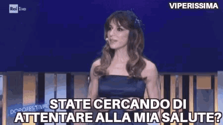 a woman in a blue dress is talking into a microphone on a stage and says state cercando di attendare alla mia salute