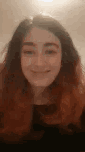 a close up of a woman 's face with long hair smiling .