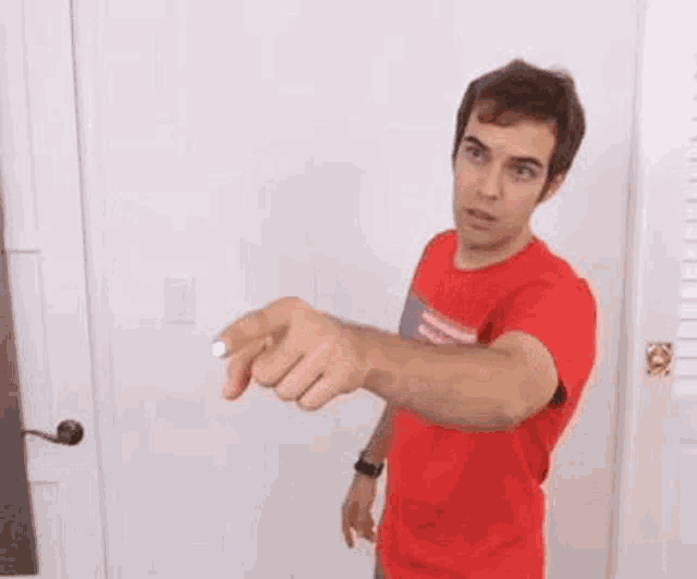 a man in a red shirt is pointing at a white circle with his finger .